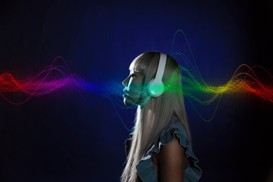 Colorful wave pattern around young woman listening music over blue background
