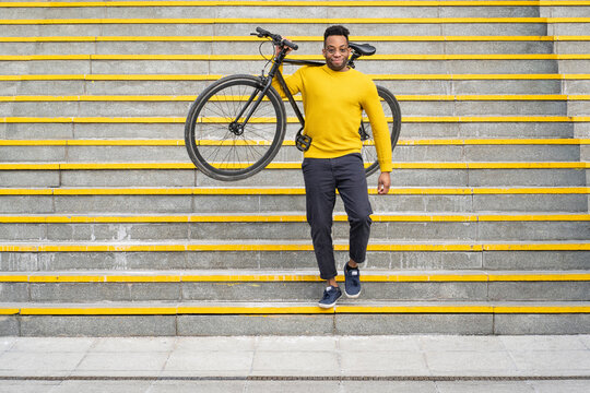 Man carrying bicycle while moving down from staircase