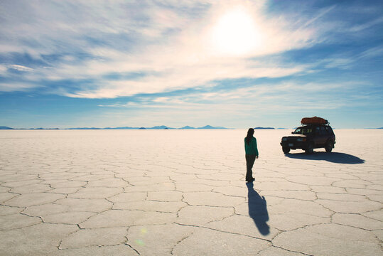 Bolivia, Potosi, Woman walking towards her 4x4 in Uyuni salt flats