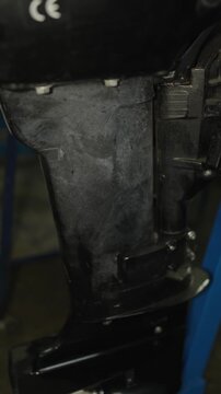 A close-up shot of a black outboard boat motor leg and lower unit housing, showing scuffs and dust from use.