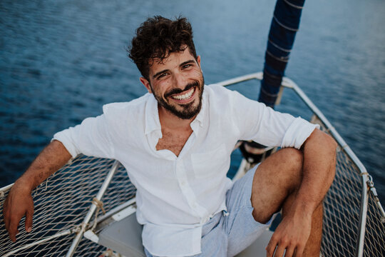 Smiling sailor sitting on a sailboat in the Mediterranean Sea