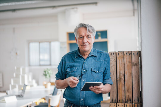 Portrait of senior businessman holding tablet in office