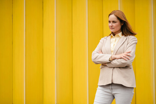 Confident businesswoman standing outdoors against yellow background