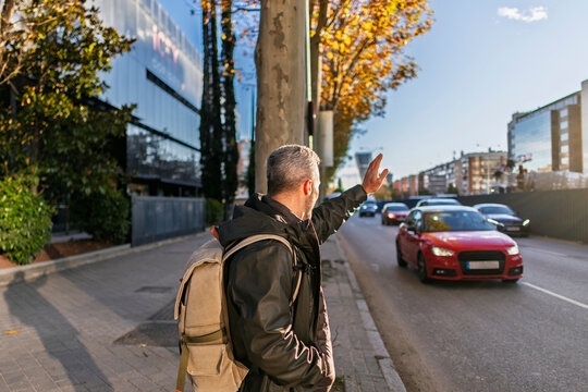 Person waiting at bus stop waving for public transport in urban street