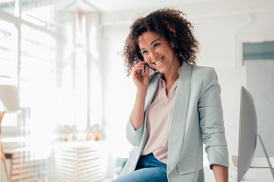 Happy businesswoman talking through headset at office