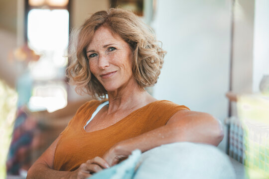 Smiling mature woman sitting on sofa at home