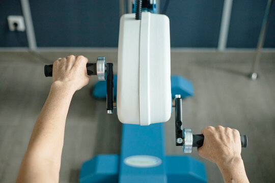 Female patient uses an arm ergometer for physical therapy indoors