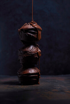 Liquid chocolate dripping on stack of three chocolate muffins