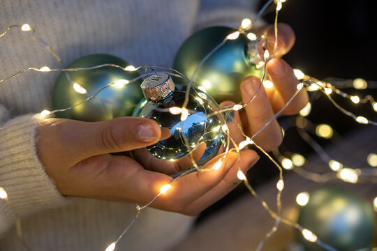 Hands of little girl holding Christmas ornaments