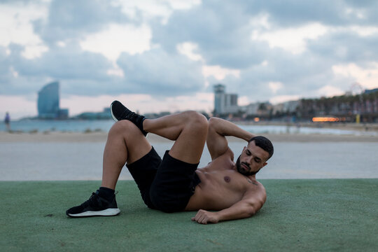 Barechested muscular man doing workout outdoors
