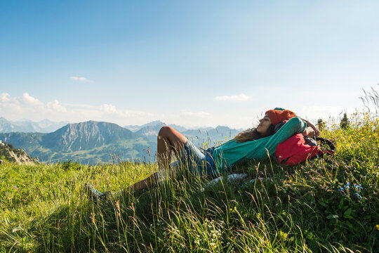 Austria, Tyrol, Tannheimer Tal, young woman lying on alpine meadow