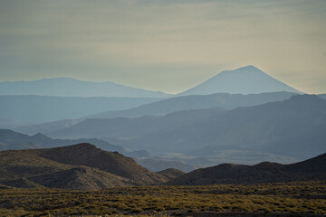 Naklejka premium Layered mountain ranges with distant volcano in atmospheric haze
