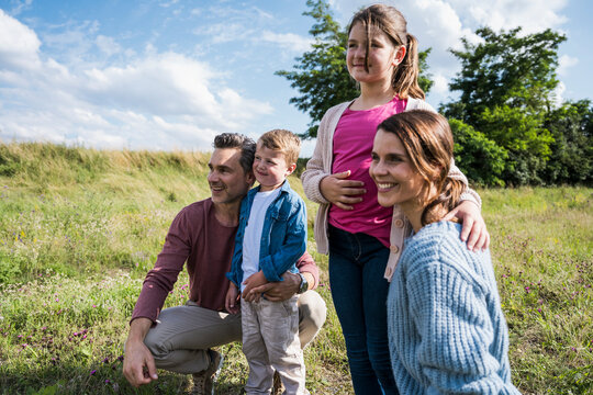 Happy parents and children smiling together in a summer meadow