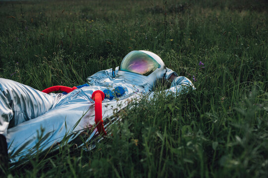 Spaceman exploring nature, relaxing in meadow