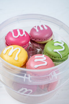 Colorful decorated macarons placed inside transparent plastic storage box
