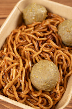 Saucy stir-fried noodles served with beef meatballs in a kraft paper takeout box