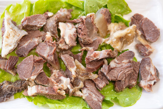 Sliced cooked beef placed on fresh lettuce over a white plate