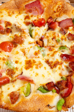 Luxury supreme pizza topped with melted cheese, ham, sausages, cherry tomatoes and bell peppers