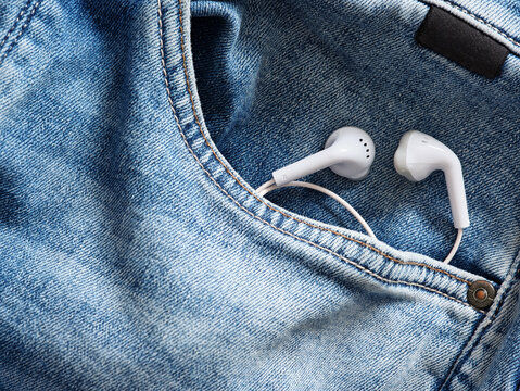 White earbuds peeking from blue jeans pocket