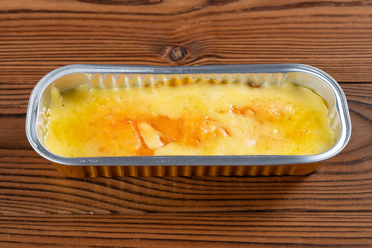 Baked cheese custard dessert resting inside a rectangular aluminum foil tray on wooden table