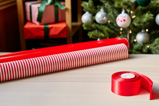 Christmas gifts preparation table with wrapping paper, gift, ribbon and xmas balls. Festive mood.