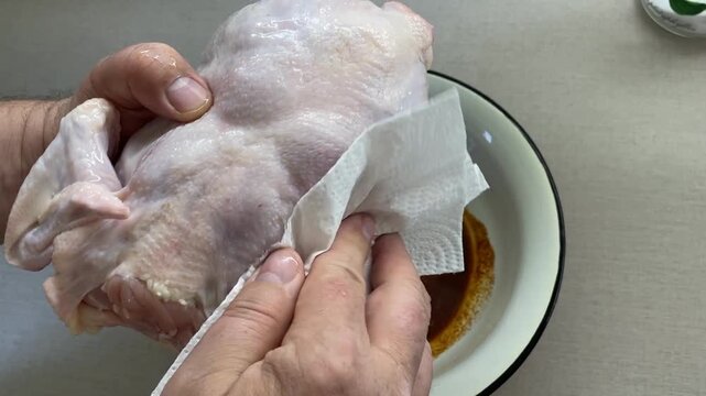 Raw chicken on a plate with marinade being prepared for cooking in a kitchen setting