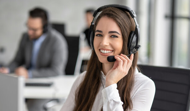 Portrait of a beautiful smiling female customer support agent with a headset in the office