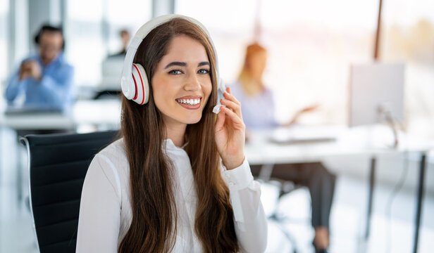 Happy young woman working as a customer support agent in a bright office