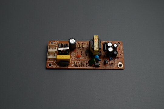 An electronic power supply circuit board module with various components mounted on it, set against a dark gray background.