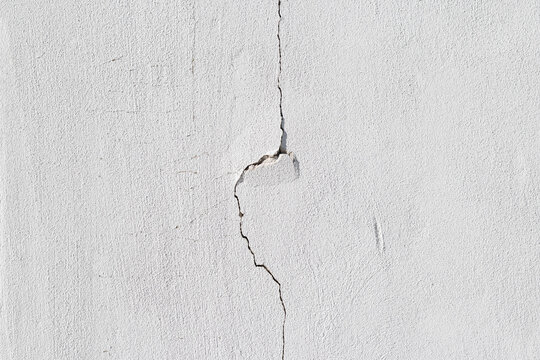 background texture of a cracked white concrete wall with damaged cement surface
