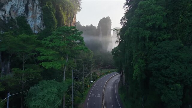 Aerial view of a scenic road through limestone karst mountains and morning mist in Krabi, Thailand
