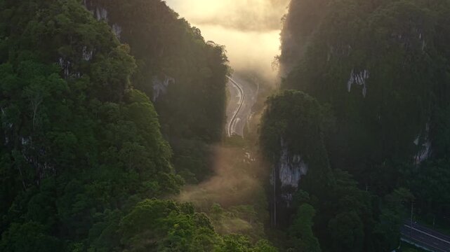 Aerial view of a scenic road through limestone karst mountains and morning mist in Krabi, Thailand