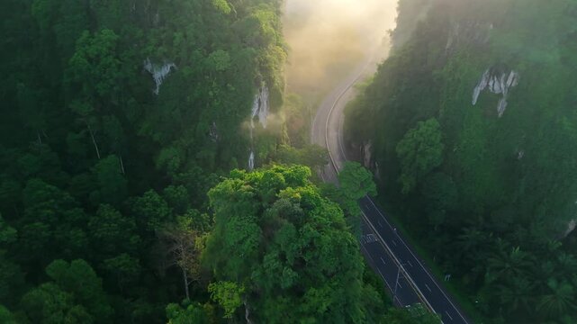 Aerial view of a scenic road through limestone karst mountains and morning mist in Krabi, Thailand