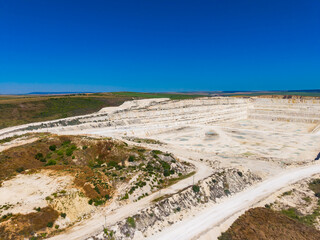 Fototapeta premium Quarry site with layered stone and clear blue sky seen in the distance during daytime