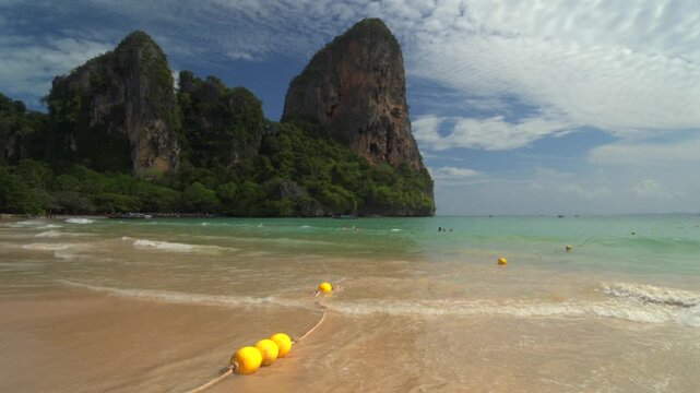 Beautiful tropical Railay beach with limestone cliffs and traditional longtail boats in Krabi, Thailand.