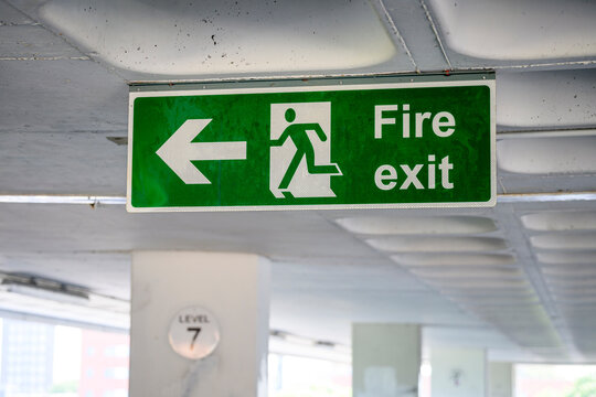 Green fire exit sign featuring a left arrow and running man symbol, car park garage