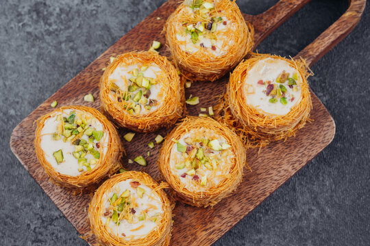 Middle Eastern Kataifi desserts with pistachios on wooden board