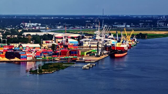 Riga, Latvia - 26 August 2025: Aerial view of the busy port of Riga with cargo ships, shipping containers, and industrial cranes along the Daugava River.
