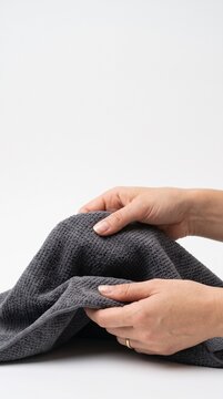 Close up of hands holding a textured dark grey fabric with a white background Silhouette