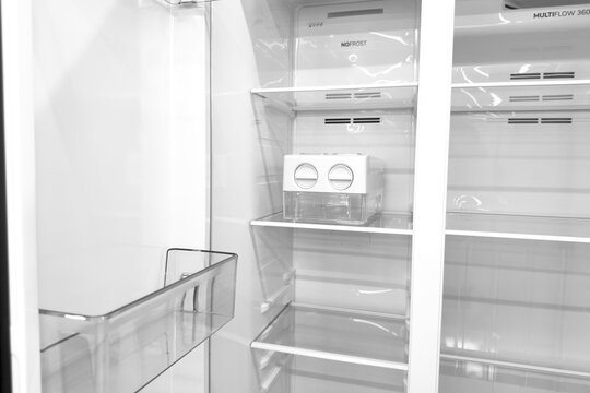 Modern empty refrigerator interior showing clear shelves and ice maker