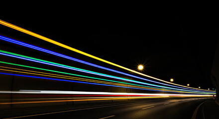 Fototapeta premium A long exposure photograph captures the streaks of light from passing vehicles within a tunnel.