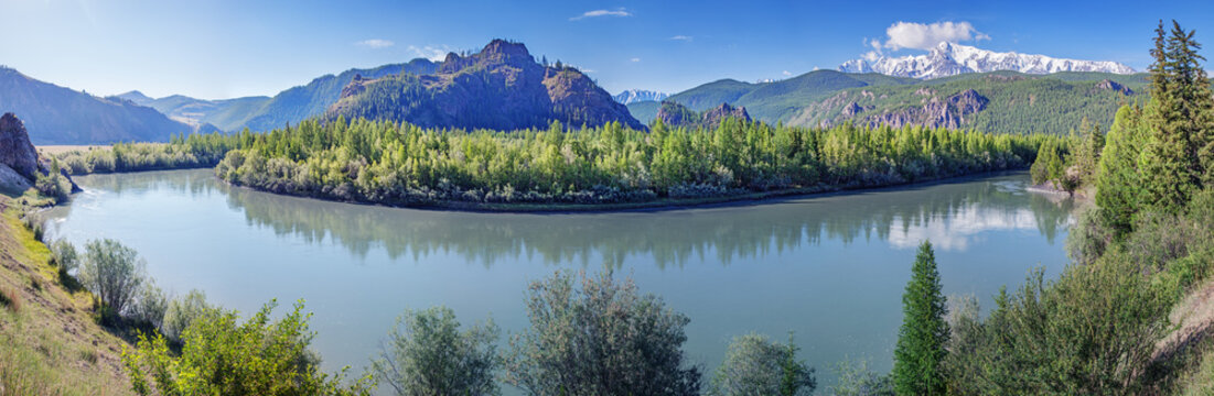 Mountain valley with a river, snow-capped peaks and green forests, panoramic view, summer travel