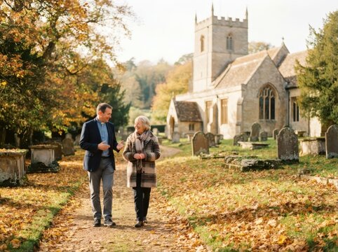 Priest speaking with woman walking in churchyard on autumn day. Clergyman offering emotional support to senior parishioner. Religion pastoral care and community faith concept.