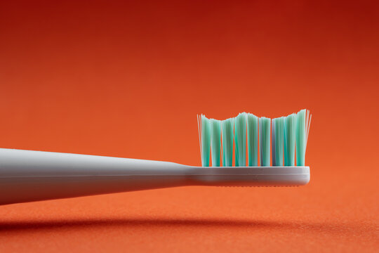 Toothbrush head with green bristles on orange background