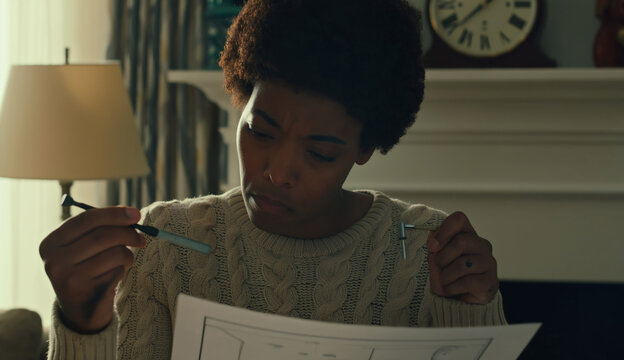 Confused woman reading assembly instructions while holding tools at home