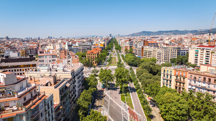 Naklejka premium Aerial view of central Barcelona featuring the historic bullring, wide boulevards, modern cityscape and the Mediterranean Sea on a sunny summer day.