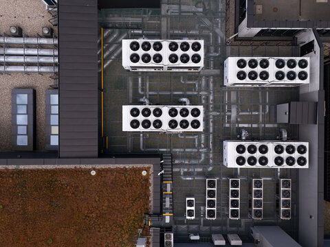Aerial view of a data center roof featuring multiple industrial HVAC cooling units, ventilation pipes, and a green roof section in Gdansk, Poland.