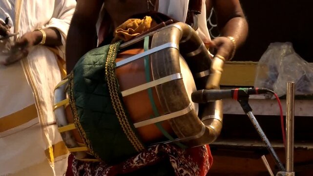 Closeup of an artist playing Thavil (Thakil), a South Indian percussion musical instrument during the night procession in a temple festival in Kerala, India