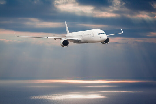 Airplane flying over tropical sea at sunset