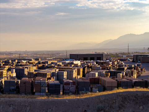 Aerial view of a masonry block loading area with stacks of pavers and construction materials in a yard at sunset in Bluffdale, Utah, United States.
